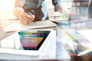 Mediendesigner bei der Arbeit an Laptop und Tablet