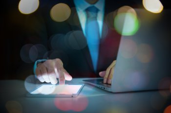 Geschäftsmann arbeitet mit Laptop und Tablet