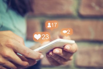 Person, die Smartphone in der Hand hält und soziale Netzwerke nutzt.