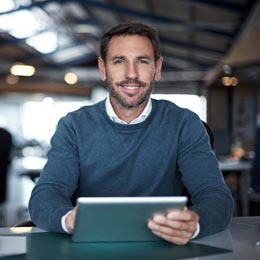 Mann mittleren Alters hält ein Tablet in den Händen