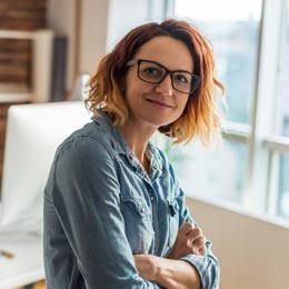 Frau mittleren Alters mit Brille und verschränkten Armen