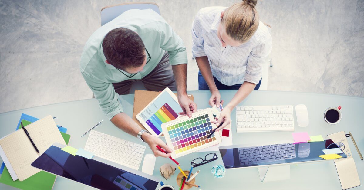 Zwei Grafiker sitzen zusammen am Schreibtisch und beratschlagen sich