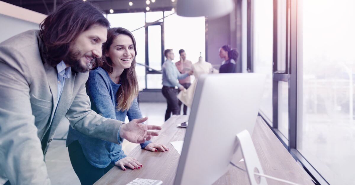 Duale Studentin und Kollege sitzen zusammen vor Computer