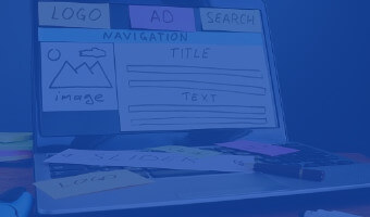 Webdesigner hat auf Monitor die verschiedenen Module einer Webseite mit Papier nachgebaut